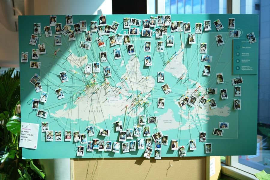 A wall map covered in attendee photos linked by string